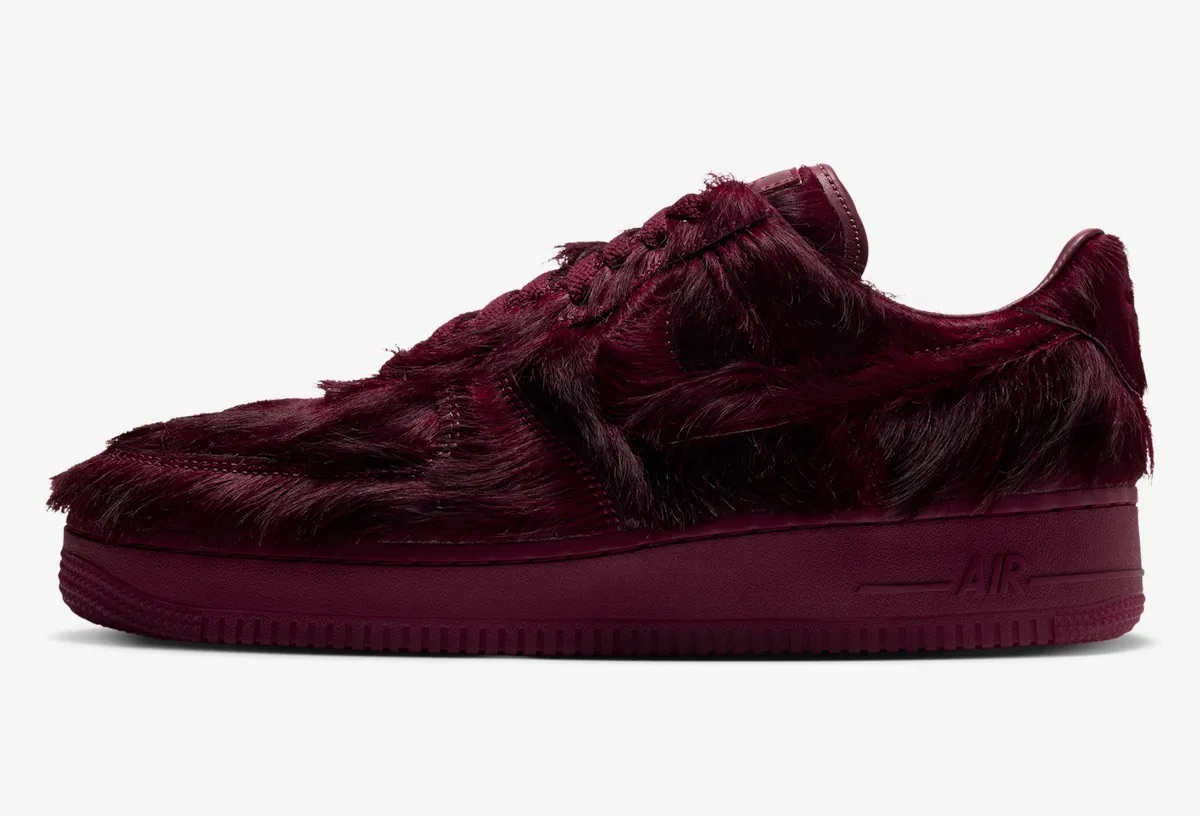 Nike Air Force 1 Low Pony Hair Team Red de perfil sobre fondo gris claro, con el pelo largo bordó tapando el Swoosh y los paneles, y la palabra Air en relieve sobre la mediasuela del mismo color