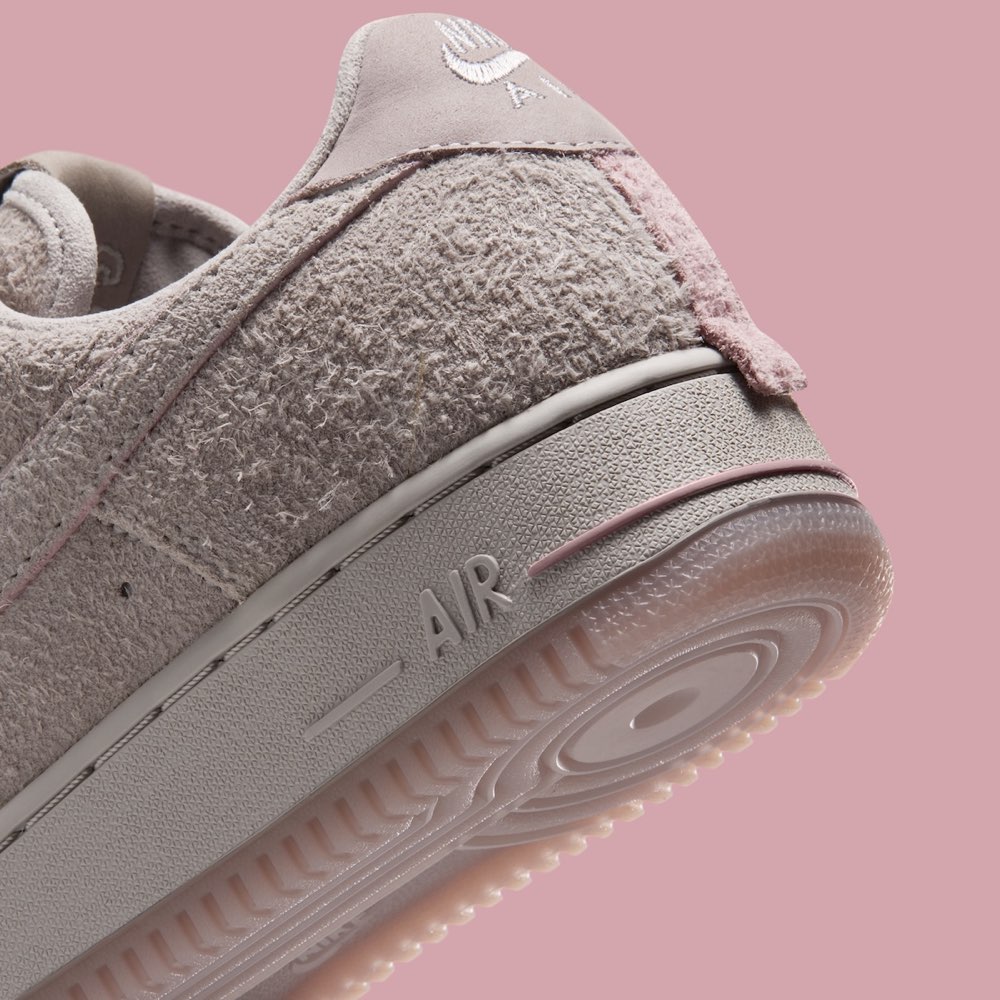 Detalle del talón del Nike Air Force 1 Subway Rat con la tira rosa que imita la cola de una rata, la gamuza gris de pelo largo y la suela translúcida rosa