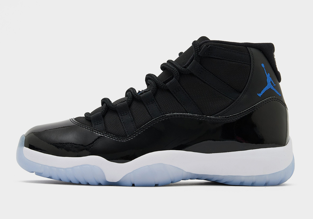 Air Jordan 11 Space Jam 2026 de perfil con charol negro, Jumpman Varsity Royal y suela translúcida