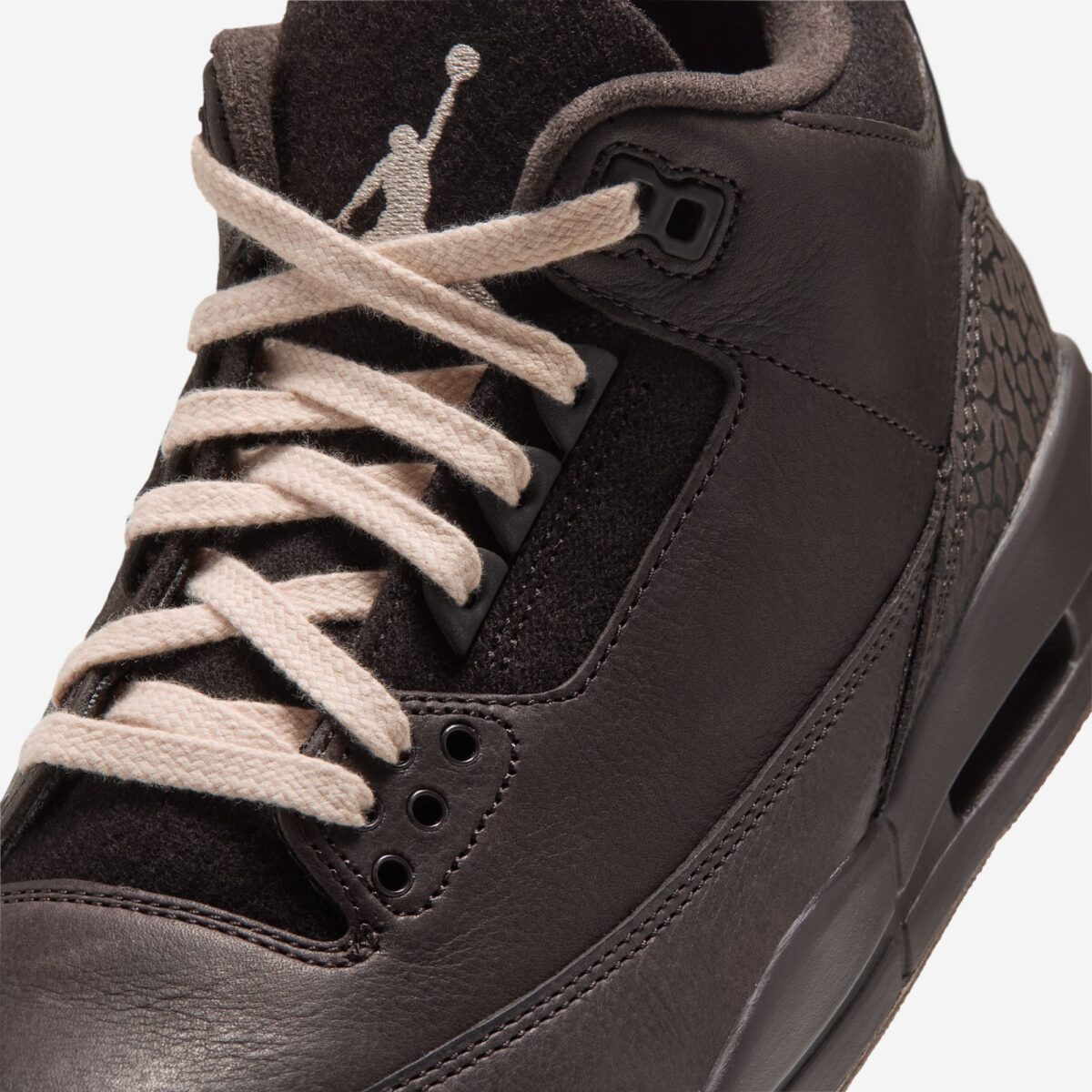 Primer plano del Air Jordan 3 Fireside con cordones crema cruzados, Jumpman beige bordado en la lengüeta marrón, ojales oscuros, cuero marrón con textura y el elephant print en el mismo tono cerca del talón