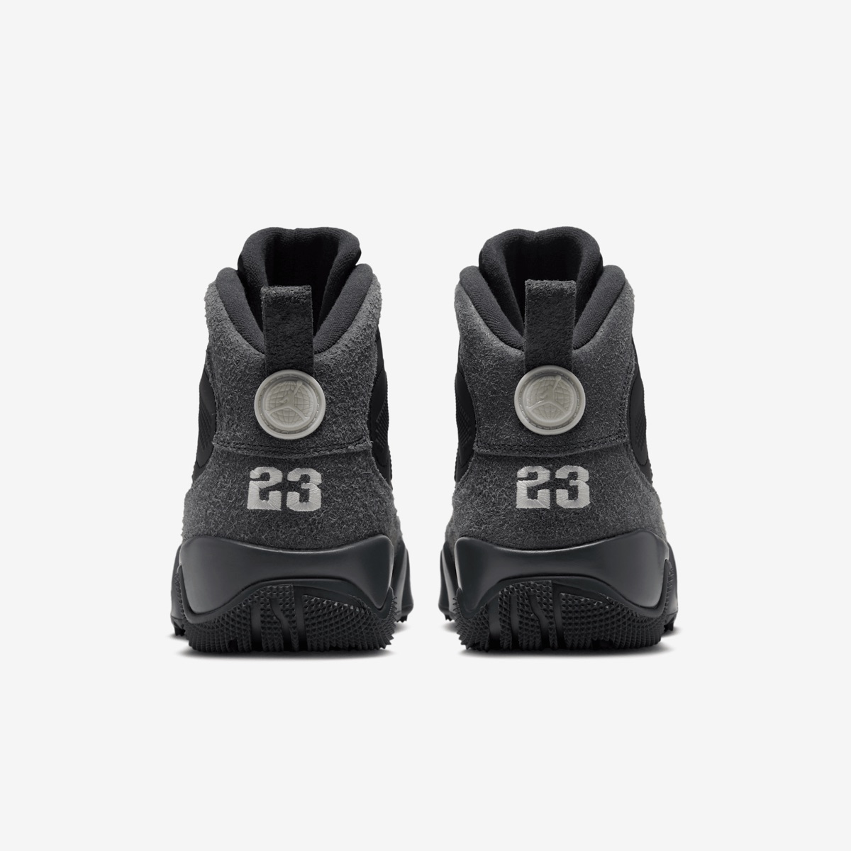 Vista trasera del par del Air Jordan 9 Retro Boot NRG Anthracite sobre fondo blanco, con la gamuza gris oscura, el número 23 en gris claro sobre cada talón, el disco con el logo arriba y la suela negra con tacos