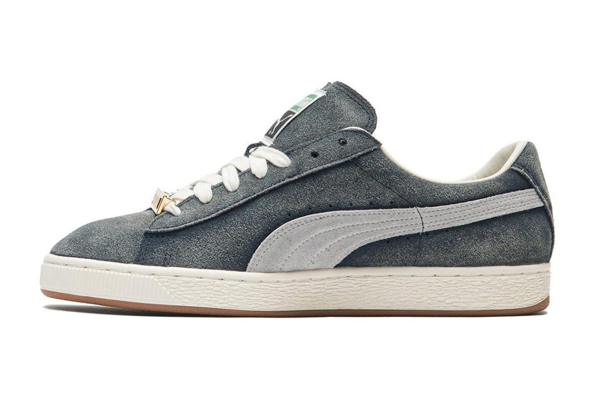 A$AP Rocky x PUMA Suede '94 Faded Blue de perfil sobre fondo blanco, con gamuza azul gastada, Formstrip gris, cordones blancos, chapita dorada y mediasuela blanca con suela de goma marrón