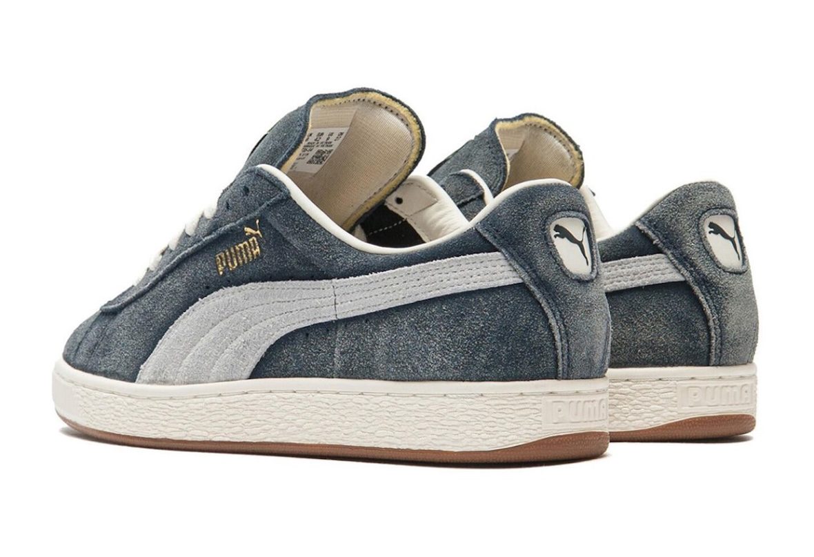 Par de A$AP Rocky x PUMA Suede '94 Faded Blue visto de atrás y de costado sobre fondo blanco, con el talón de gamuza azul, el logo del felino de PUMA y el forro color crema