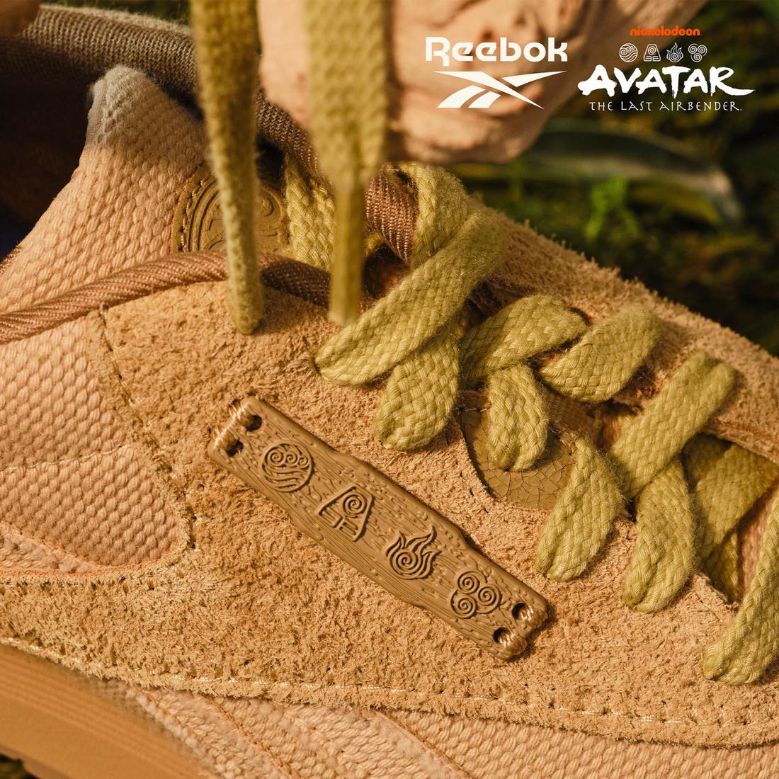 Detalle de la Reebok Classic Nylon Avatar en gamuza tostada, con una placa marrón que muestra los símbolos de las cuatro naciones y cordones gruesos verde oliva