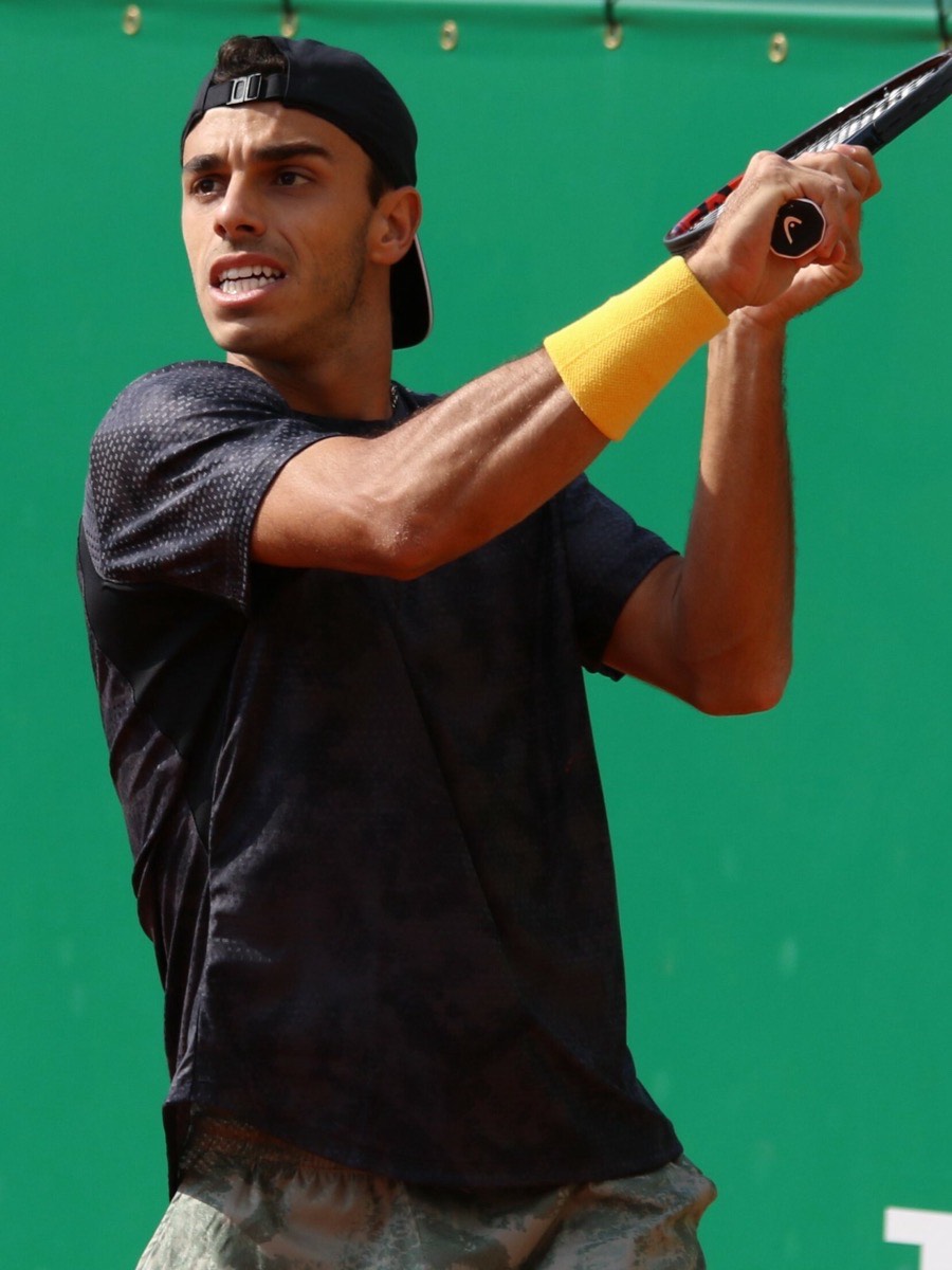 Foto de archivo: Francisco Cerúndolo, con gorra negra puesta al revés, remera oscura y muñequera amarilla, sigue la pelota después de un golpe frente a una lona verde, en el Masters de Montecarlo 2023