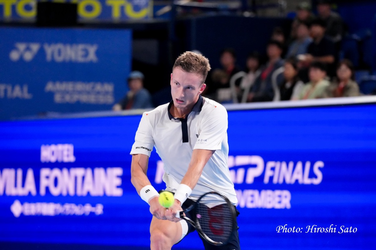Jiri Lehecka, con remera blanca con cuello negro, pega un revés a dos manos durante el Japan Open en el Ariake Coliseum
