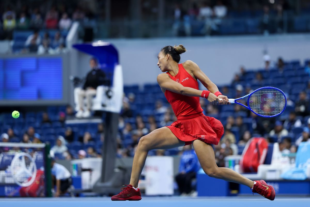 Zheng Qinwen, de rojo, estira un revés a dos manos en el estadio principal del China Open 2026