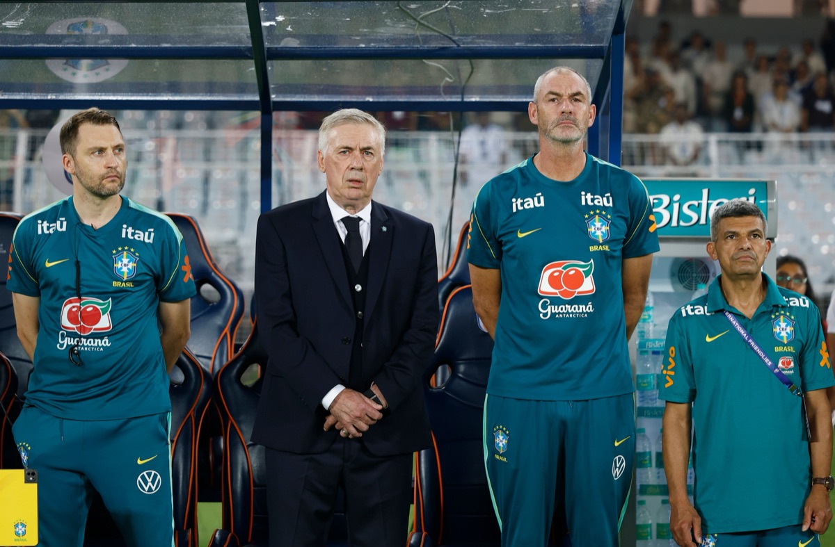 Carlo Ancelotti, de traje oscuro, junto a integrantes de su cuerpo técnico frente al banco de suplentes de Brasil en Calcuta