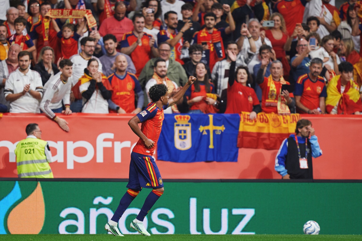 Lamine Yamal, con la camiseta roja de España, festeja con el puño en alto frente a la tribuna del Nuevo Carlos Tartiere, donde cuelga una bandera de Asturias