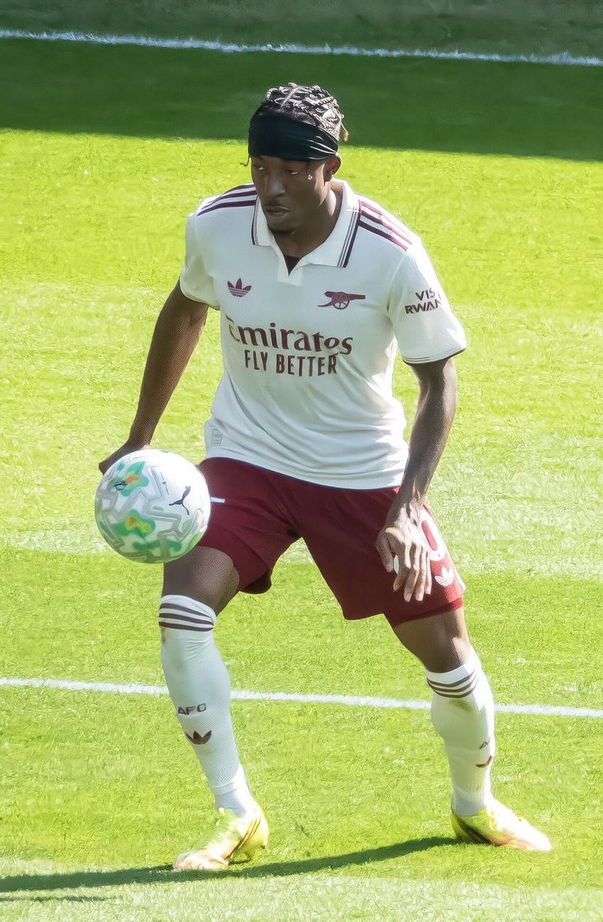 Noni Madueke, con la camiseta blanca y el short bordó del Arsenal, controla la pelota con la mano sobre el muslo durante un partido de la Premier League; foto de archivo de mayo de 2026 (foto: Chensiyuan, Wikimedia Commons, licencia CC BY-SA 4.0)