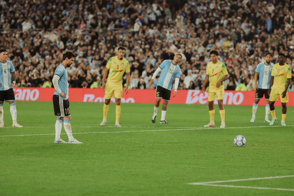 Lionel Messi, de espaldas a la cámara junto a la pelota en el punto del penal, se prepara para patear ante jugadores de Benín con camiseta amarilla, en la jugada del gol 126 en el Monumental (foto: prensa oficial de la AFA)