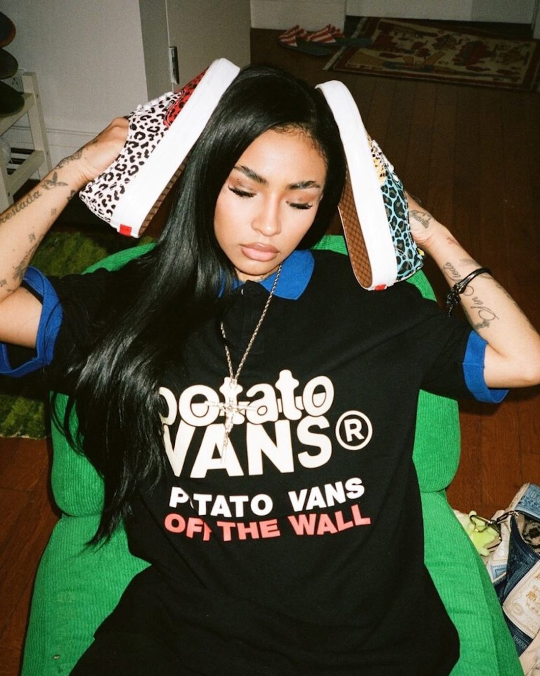 Modelo con remera negra con la leyenda Potato Vans sosteniendo los dos pies del Authentic desparejado, uno con cheetah rojo y blanco y otro con leopardo celeste