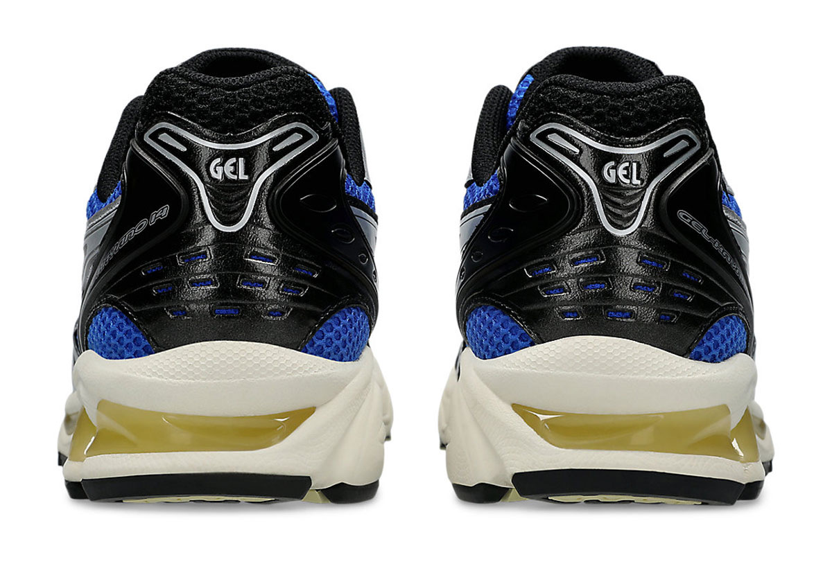 Talones del par de ASICS GEL-Kayano 14 Illusion Blue Pure Silver sobre fondo blanco, con la pieza negra con el logo GEL en plateado, la malla azul y la mediasuela crema con detalles amarillentos