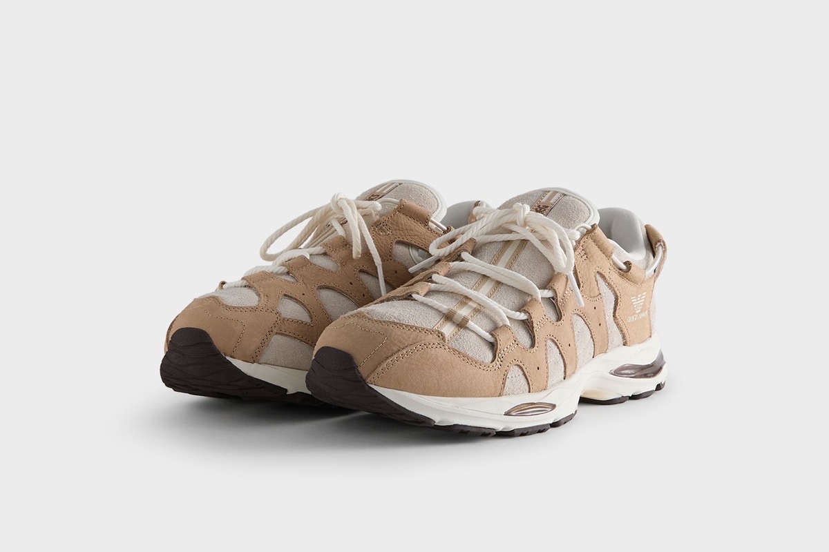 Par de la ASICS GEL-MAI 0.1 Safari de Giorgio Armani x Kith en diagonal sobre fondo gris claro, con capas de nubuck color camel sobre gamuza clara, cordones gruesos color crudo, águila de Giorgio Armani en el lateral y mediasuela blanca con detalles marrón oscuro