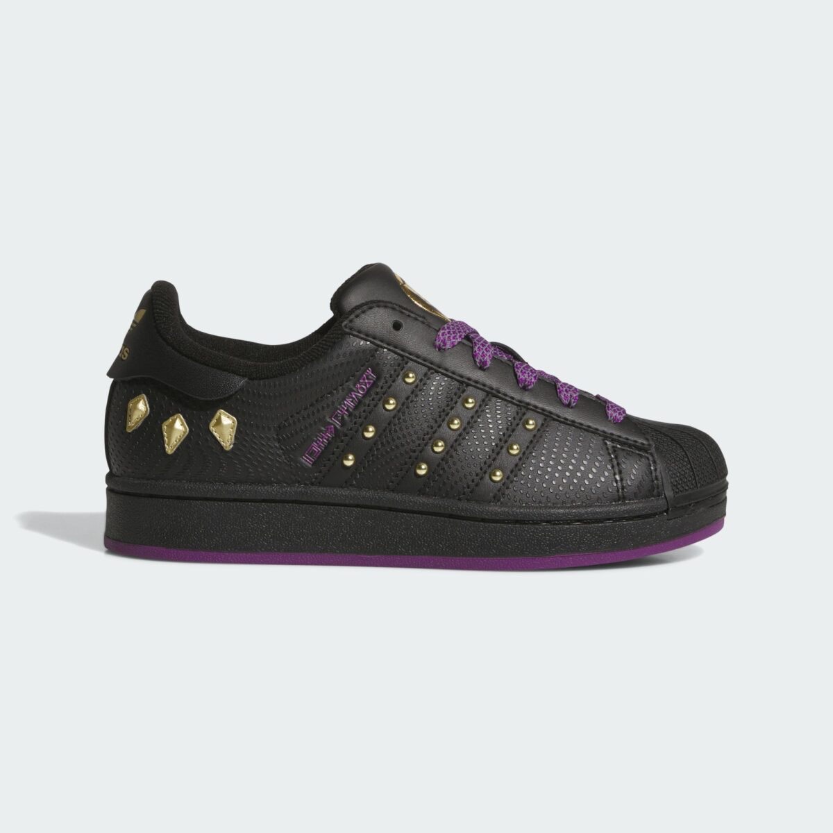 adidas Superstar Shuri Black Panther de perfil en cuero negro texturado, con tachas doradas en las tres tiras, piezas doradas en el talón, cordones violetas y suela violeta