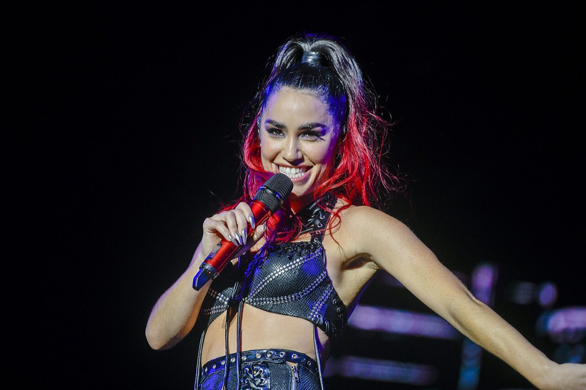 Lali sonriendo con un micrófono rojo en la mano, con el pelo atado y mechones rojos, durante un show en vivo (foto de archivo, 2023; Santiago Mazzarovich / Intendencia de Montevideo, CC BY-SA 4.0)