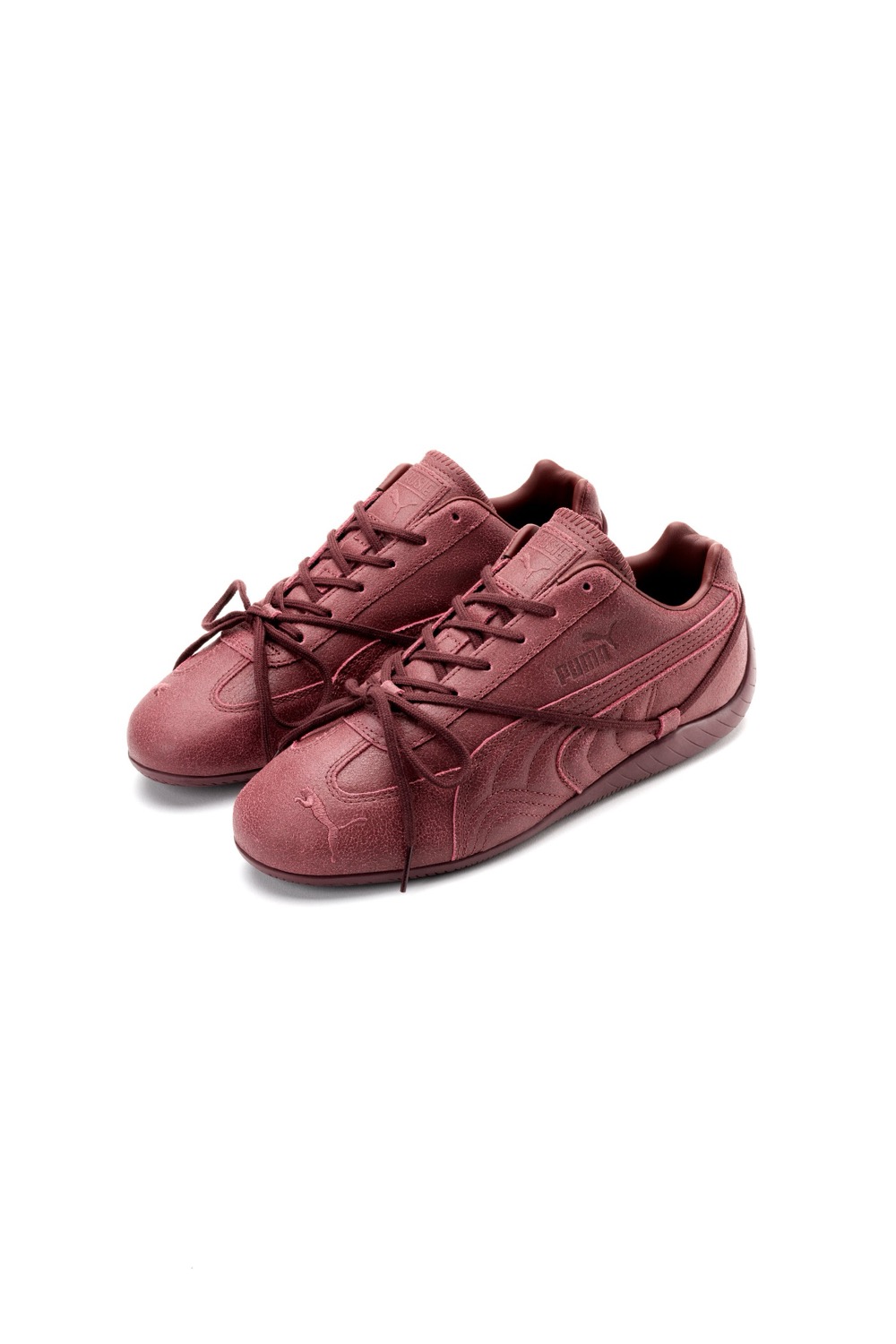 Par de PUMA x ROSÉ Speedcat VTG Burgundy sobre fondo blanco, en nobuck bordó con textura gastada, Formstrip y logo PUMA tono sobre tono y cordones largos que cruzan por encima del upper