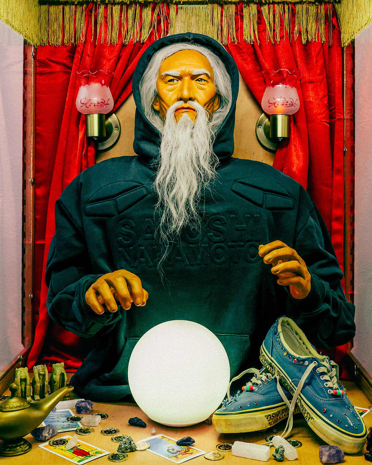 Campaña de Satoshi Nakamoto x Vans Era Lucky Charms con una figura de adivino con buzo de la marca, una bola de cristal y el par azul sobre la mesa