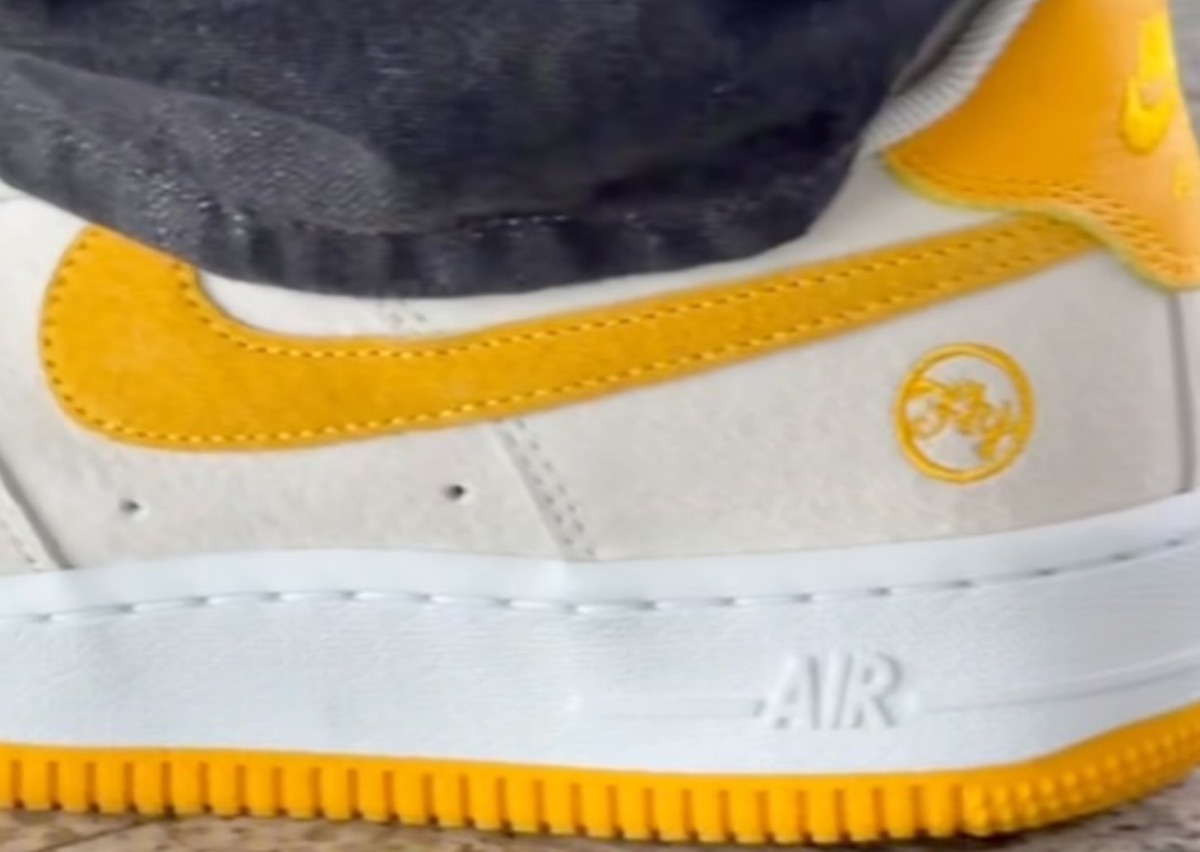 Detalle del Nike SB Air Force 1 de Fly Streetwear, con upper de gamuza clara, Swoosh de gamuza amarilla, logo circular de Fly bordado en amarillo en el talón y suela amarilla