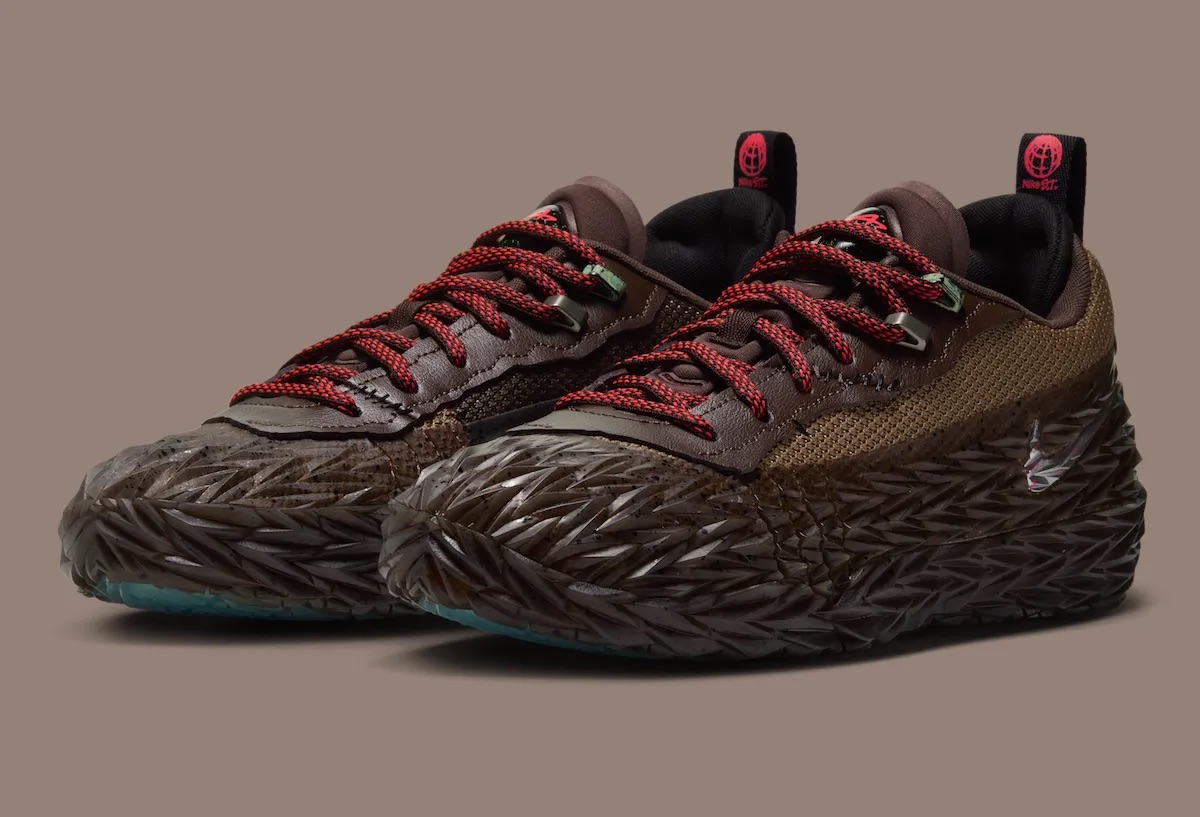 Par de Nike ST Charge Halloween de Cade Cunningham sobre fondo marrón grisáceo, con la capa de goma texturada con púas en marrón oscuro, paneles de malla tostada, cuero marrón en el sector de los cordones, cordones rojos con negro y tiradores negros con el logo Nike S.T. en rojo