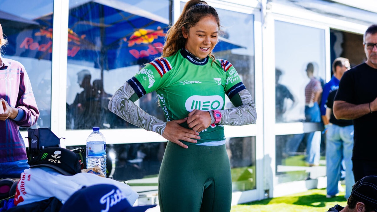 Bettylou Sakura Johnson, con la lycra verde del MEO Rip Curl Pro Portugal y la bandera de Hawái, sonríe mientras se acomoda el traje en la zona de competidores