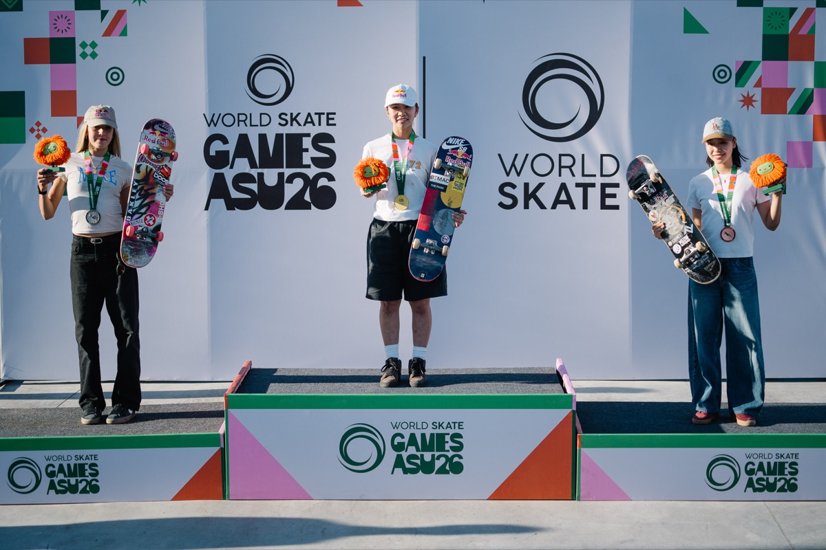 Podio femenino del Mundial de street en Luque: Yumeka Oda, con gorra y remera blancas y short negro, en el escalón más alto con su medalla de oro, entre Chloe Covell, a la izquierda, y Coco Yoshizawa, a la derecha, todas con flores naranjas y sus tablas en la mano
