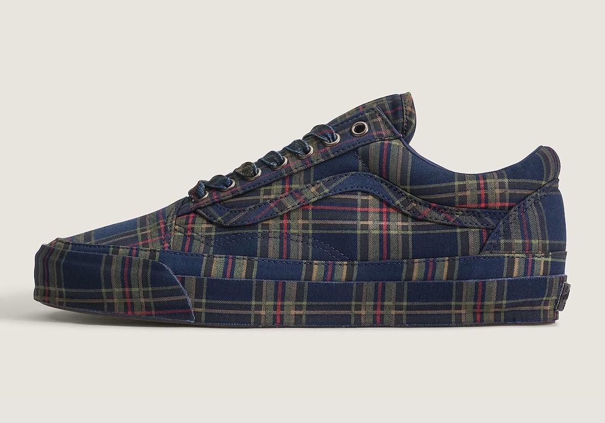 Premium Old Skool Plaid Navy/Multi de perfil sobre fondo crema, cubierto de cuadros azul marino con líneas verde oliva y rojas en el upper, el Sidestripe y la mediasuela, con cordones azules y ojalillos metálicos